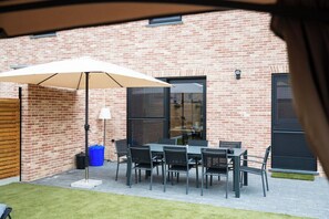 A patio with a table and chairs, a lamp, and a large umbrella. - Klein Lauw 39 in calm area of Haspengouw (Tongeren-Borgloon)