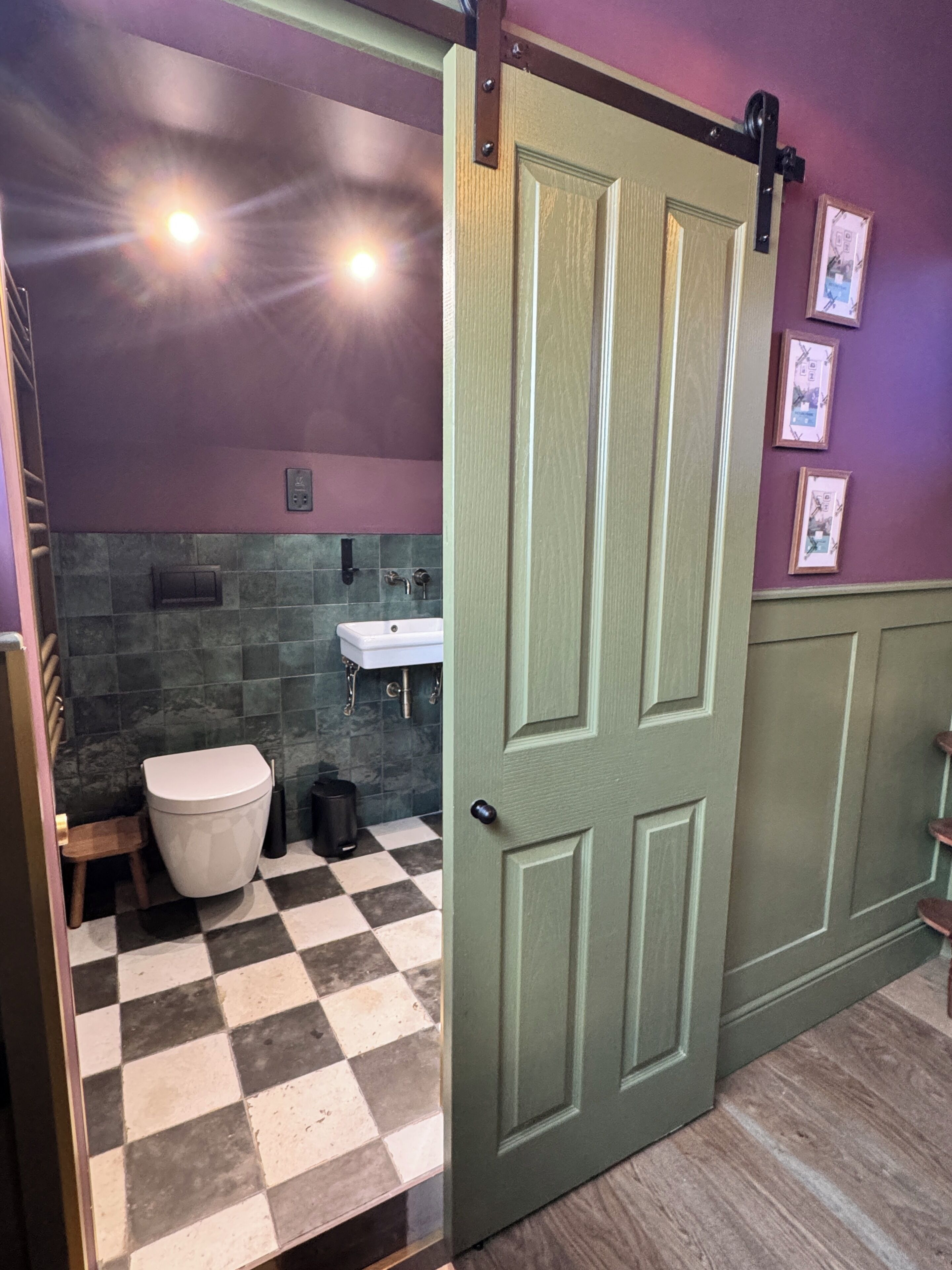 Un baño con piso a cuadros, un inodoro, un lavamanos y una puerta.