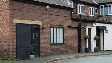A brick house with a black front door, a small window, and a number plaque.