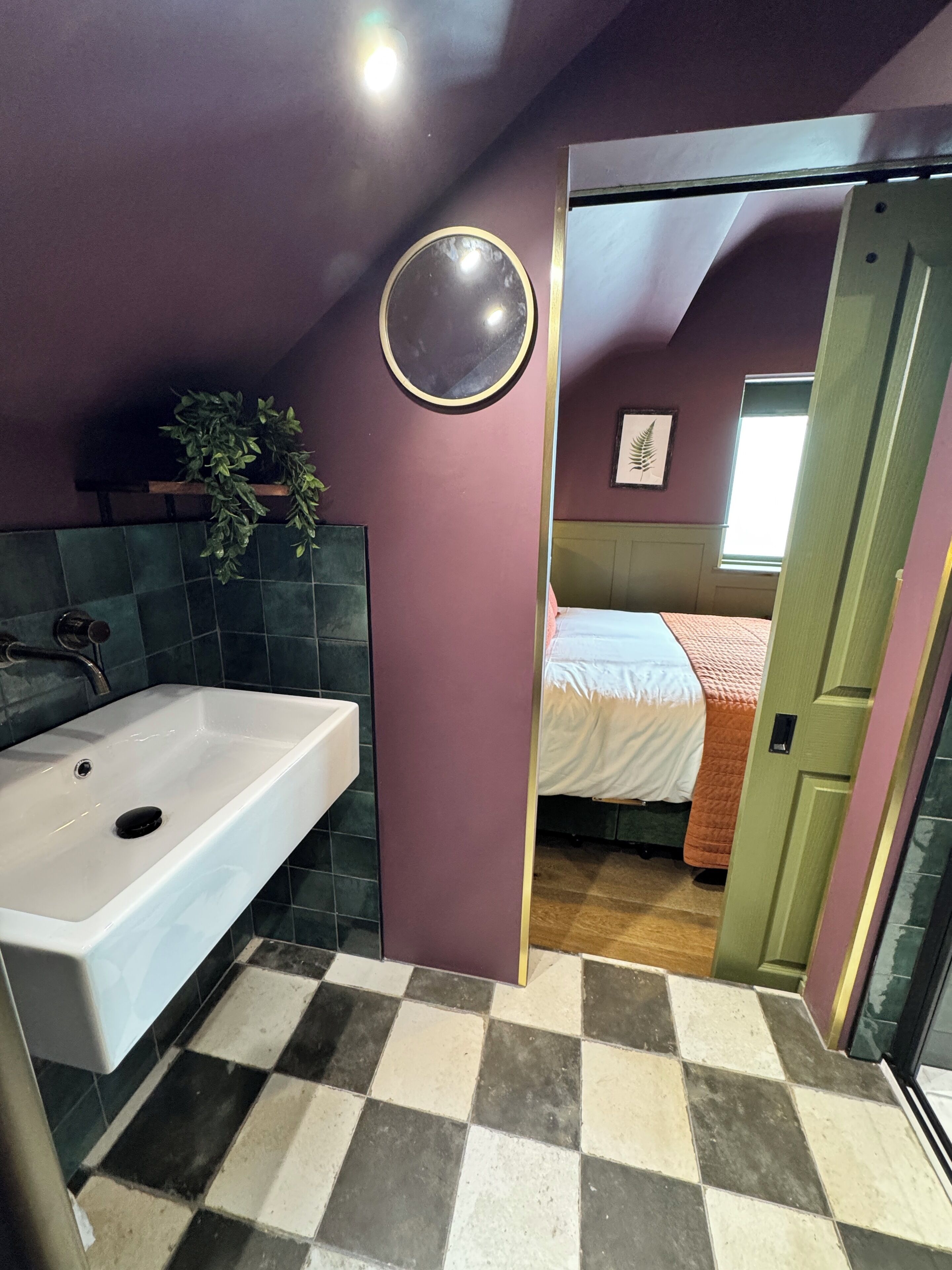 A bathroom with a white sink, a mirror, and a potted plant.