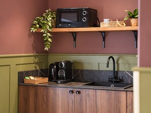 A compact kitchen with a microwave, coffee maker, and a sink.
