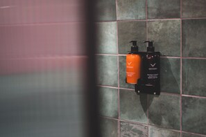 Un baño con pared de azulejos y dos botellas de champú y acondicionador.