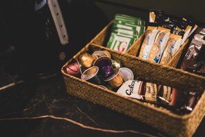 Una cesta con varios artículos, incluyendo un recipiente verde, una caja de Nescafé Gold y varias tazas pequeñas.
