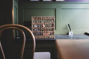 A wicker chair with a woven backrest, a white electrical outlet, and a black object on a dark surface.