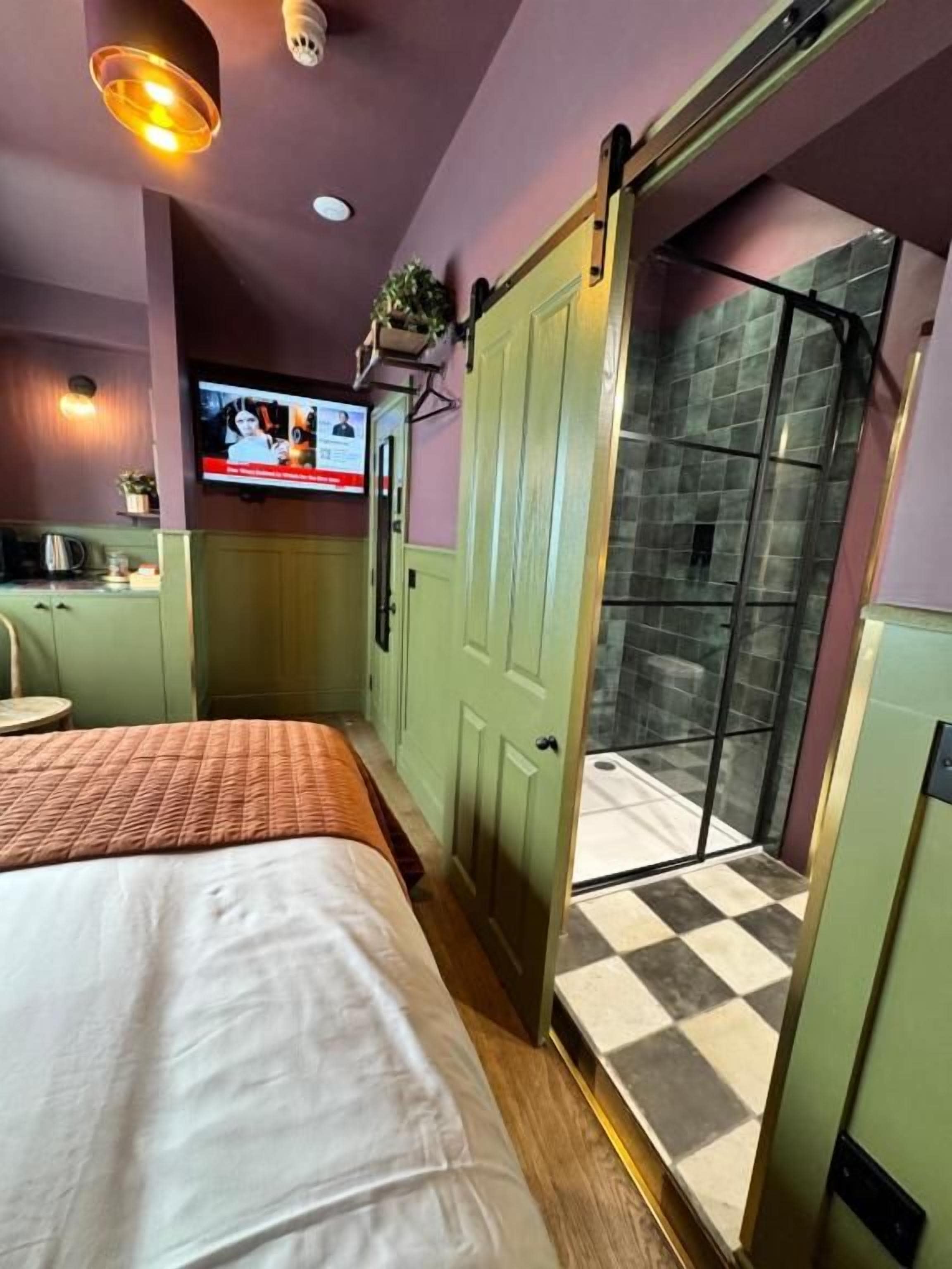 Una habitación de hotel con una cama, un televisor, una puerta verde y un piso a cuadros.