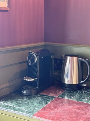 A kitchen area with a coffee maker and a kettle on a countertop. - The Linen Rooms (Knutsford)