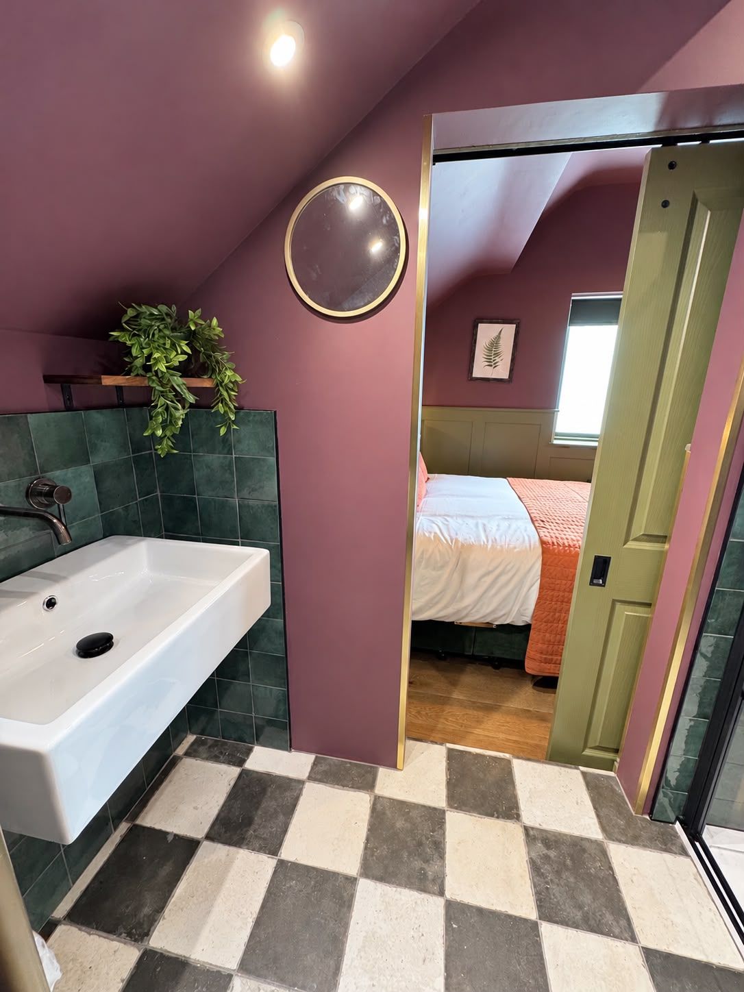 A bathroom with a white sink, a mirror, and a potted plant.
