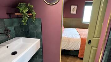 A bathroom with a white sink, a mirror, and a potted plant.
