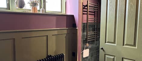 A room with a radiator, a bed, a window with a view, and a door leading to a staircase.
