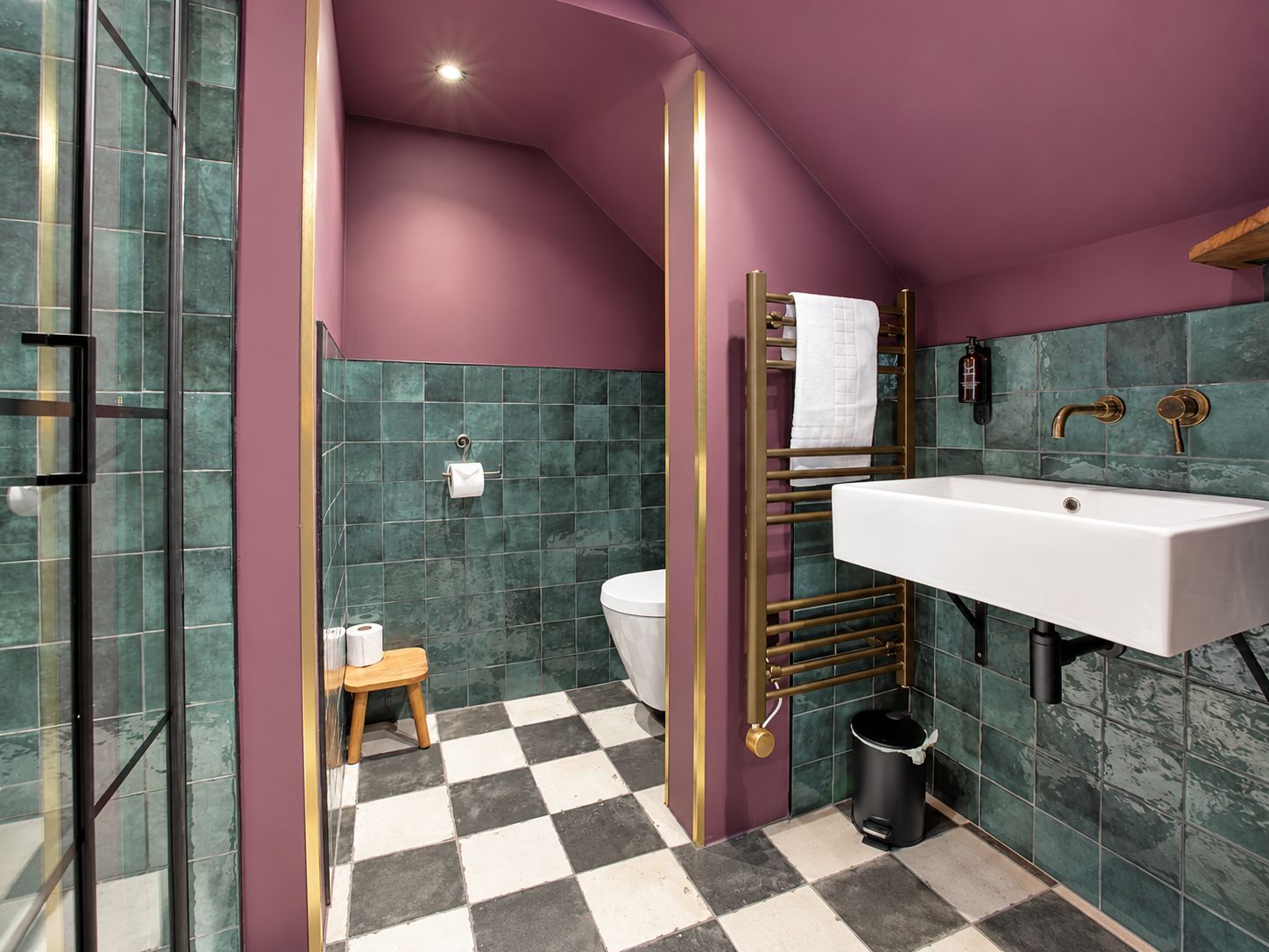 A bathroom with a checkered floor, a white sink, a towel rack, and a toilet.