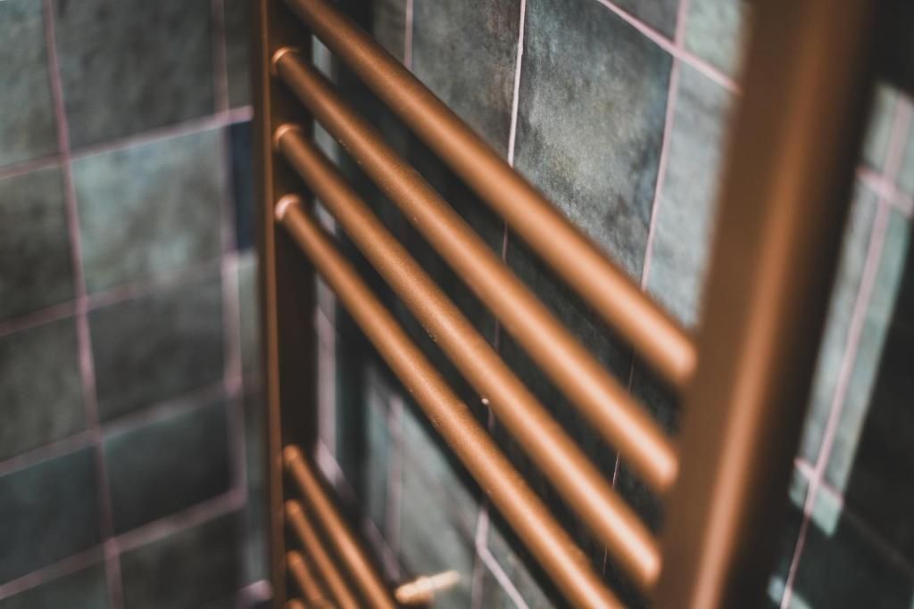 Un gros plan d’un radiateur métallique orné d’un motif en grille sur un mur carrelé.