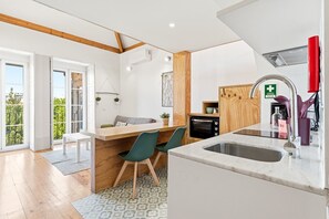 A modern kitchen with a built-in oven, a sink, and a dining area with two chairs. - GuestReady-Cosy Studio with Balcony in Porto (Porto)