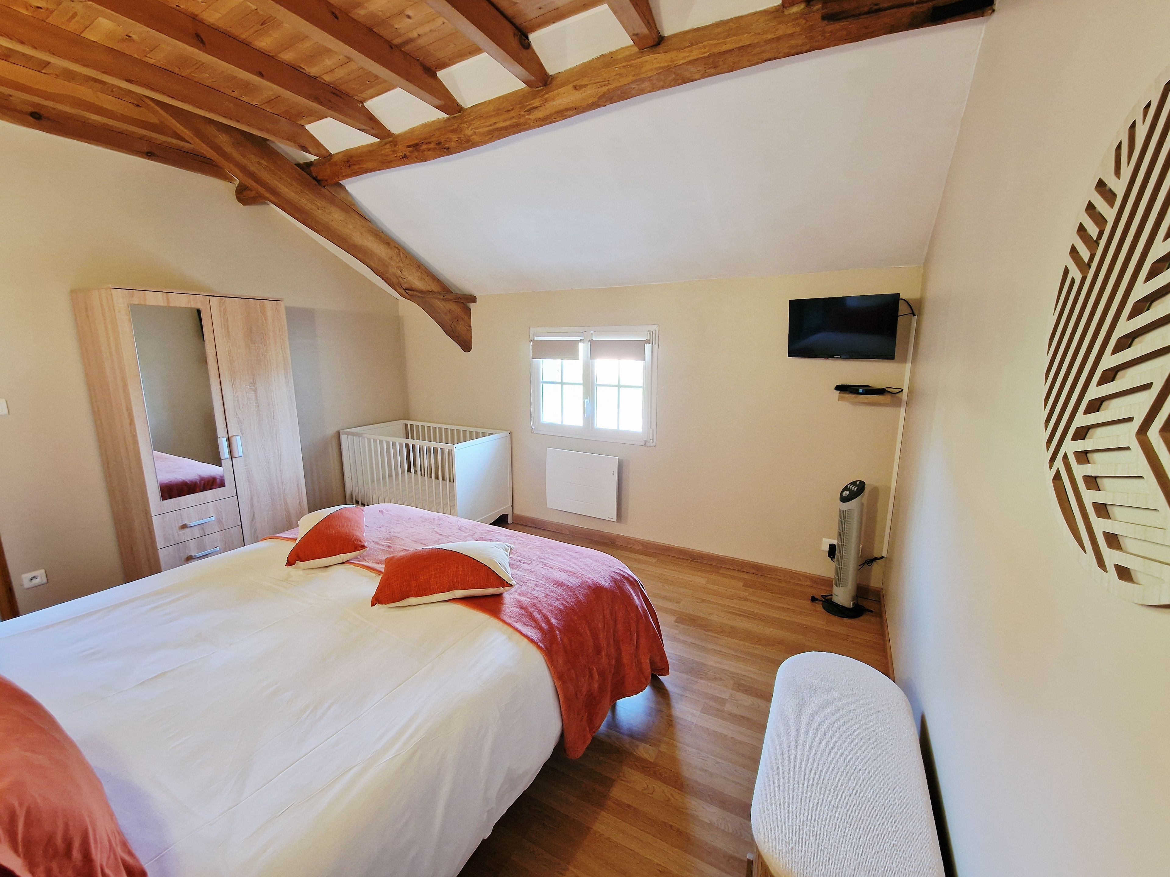 Quarto com cama grande, berço, televisão e aquecedor.