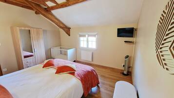 Quarto com cama grande, berço, televisão e aquecedor.