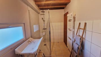 Une petite salle de bain avec une douche, une fenêtre et un étendoir.