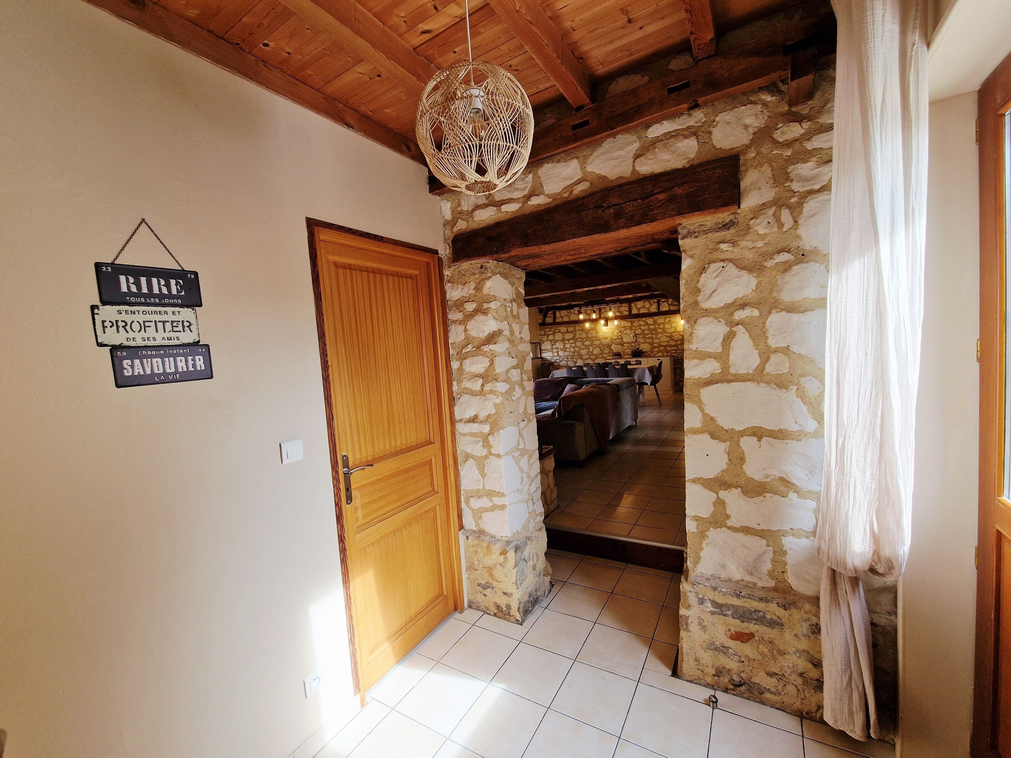 Un intérieur rustique avec un mur en pierre, une porte en bois et un luminaire suspendu.