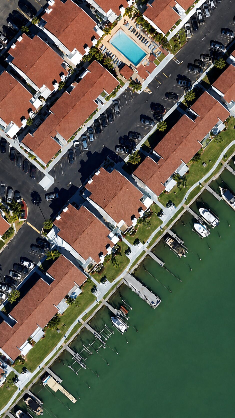 Vista aérea de uma área residencial com piscina, barcos e um porto de iates.