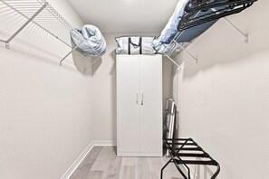 Ein Zimmer mit einem weißen Kleiderschrank, einem Wäscheständer und einem schwarzen Stuhl.