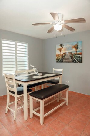 A dining area with a table, chairs, a bench, a ceiling fan, and a painting on the wall. - Family Rainforest Escape House (Río Grande)
