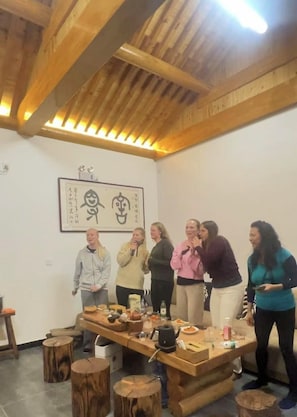 A group of people in a room with a wooden ceiling and a table with various items.