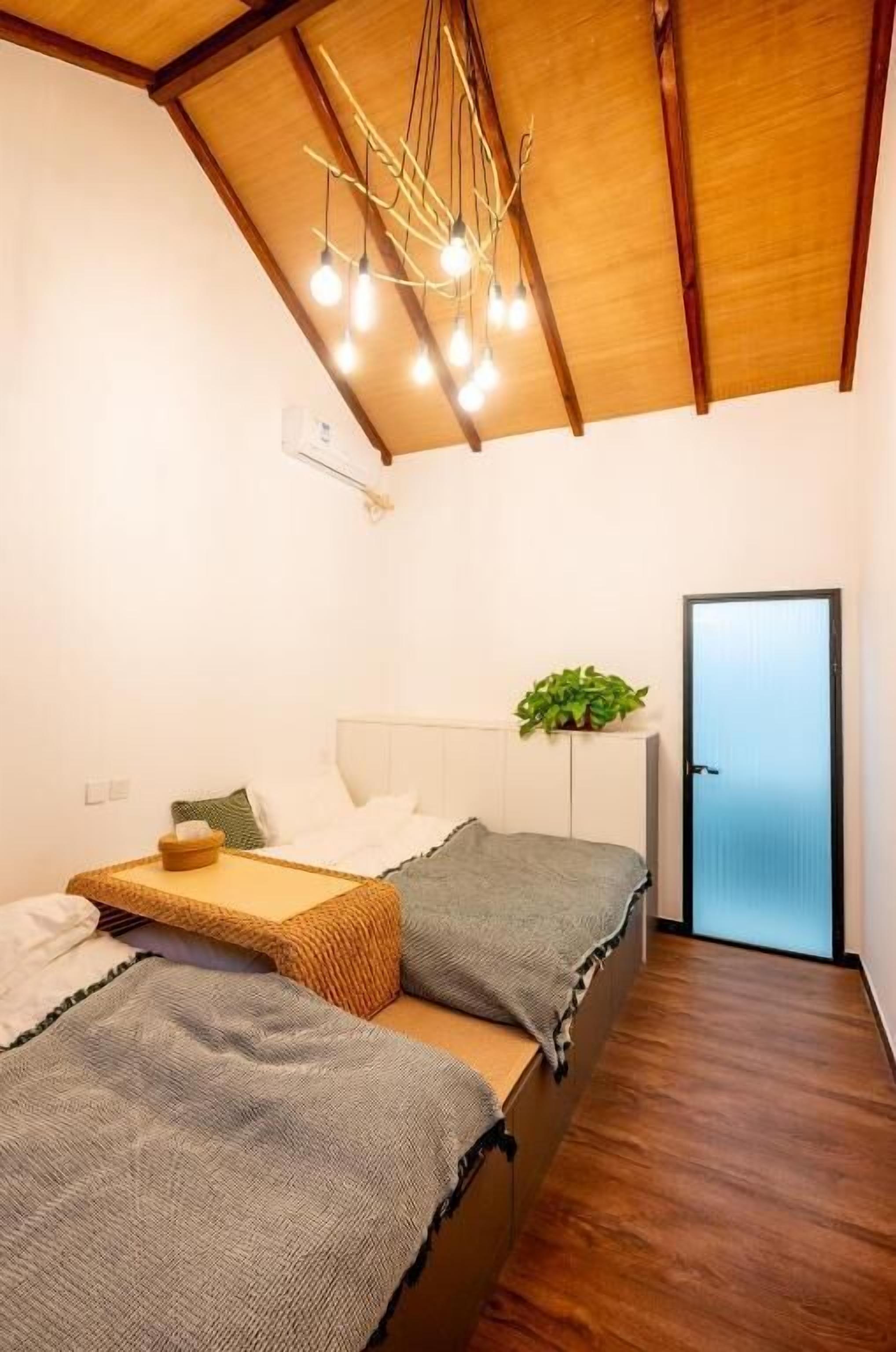 Quarto com cama, mesa de cabeceira e uma planta.