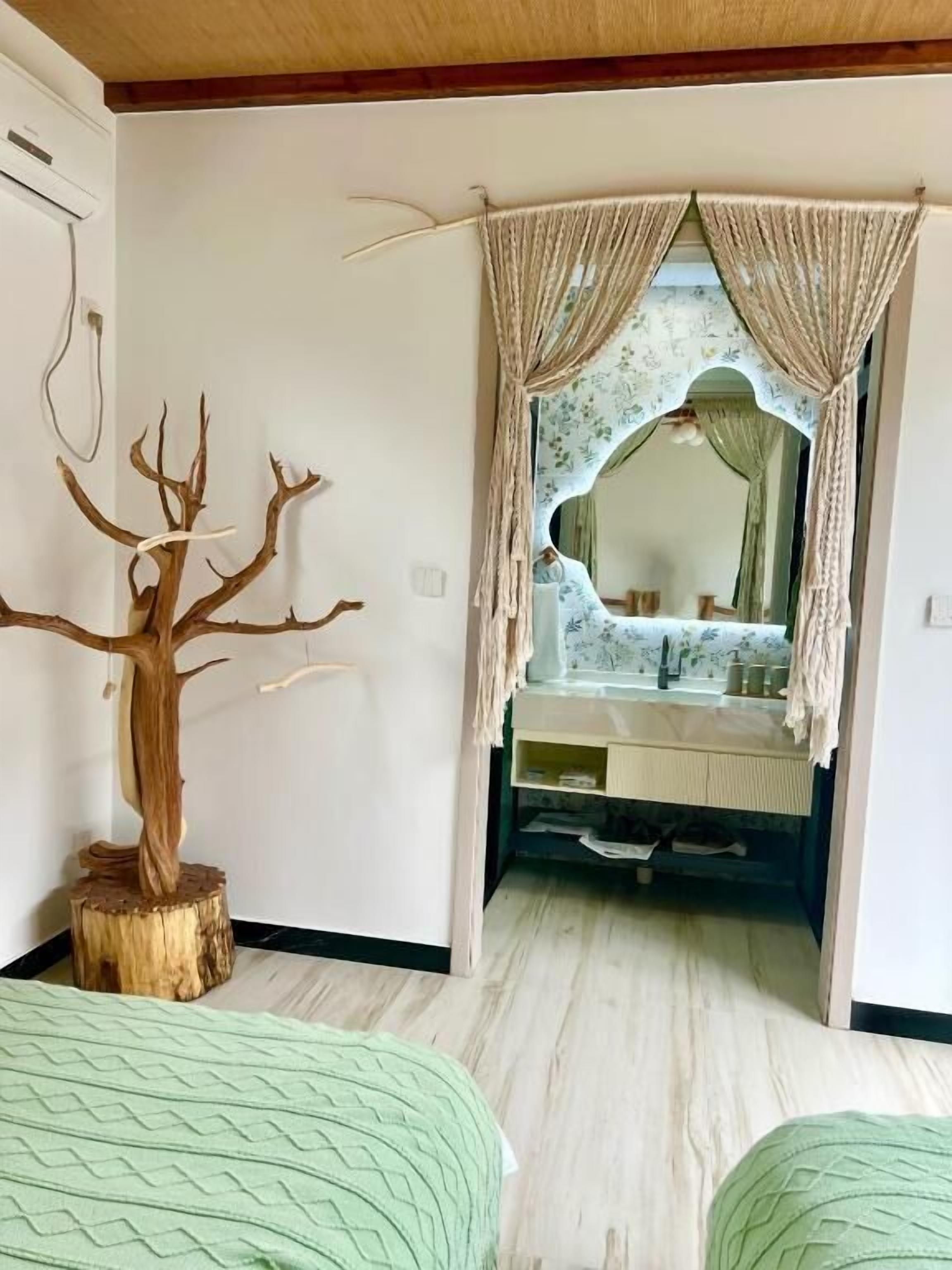 Un dormitorio con cama, espejo, escultura de árbol y tocador con espejo.