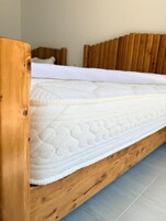 A wooden bed frame with a white mattress and a wooden headboard.