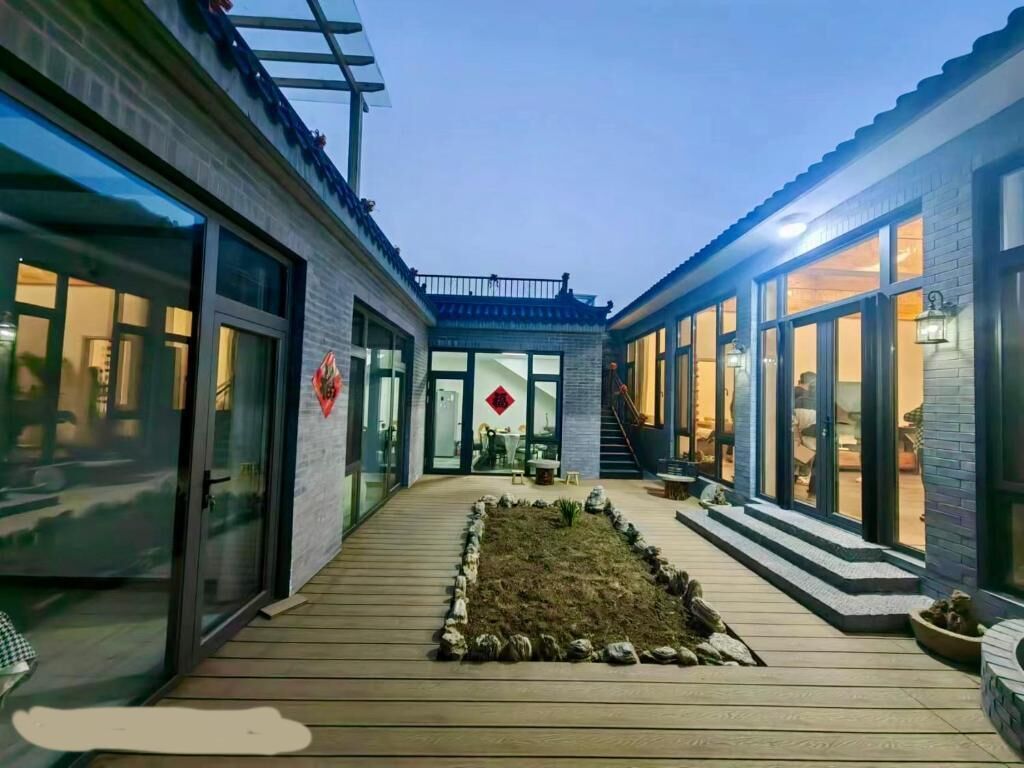 Ein Innenhof mit Holzdeck, einem kleinen Garten und einer Treppe, die zu einer oberen Ebene führt.