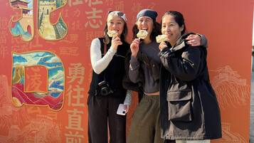Un grupo de personas frente a un muro con grandes caracteres e ilustraciones chinas.