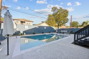 A residential swimming pool with a covered patio area, a staircase, and a fenced backyard. - Cowboy Oasis | Sleeps 7 (Houston)