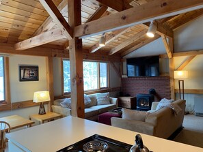 A cozy cabin interior with a fireplace, a television mounted on the wall, and a comfortable seating area. - Prime Ski-In/Ski-Out Location at Sugarloaf! (Carrabassett Valley)