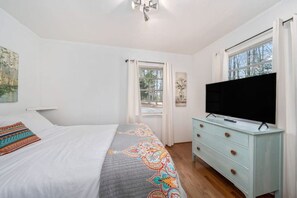 Une chambre à coucher avec un lit, une commode, un téléviseur et une fenêtre.