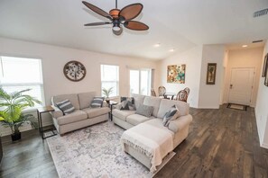 A living room with a sofa, a coffee table, and a ceiling fan. - 5 minutes to EastPort, Life Style ID's! (Sumterville)