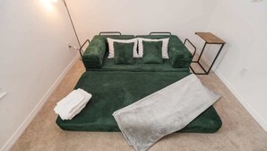 Ein Bett mit einem grünen Überwurf, einer grauen Decke und weißen Kissen.