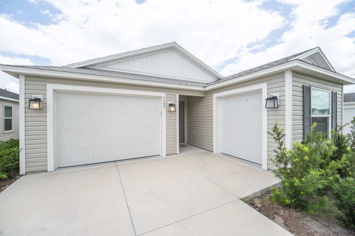 A two-story house with a garage, a covered driveway, and a landscaped front yard.