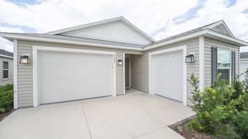 A two-story house with a garage, a covered driveway, and a landscaped front yard.