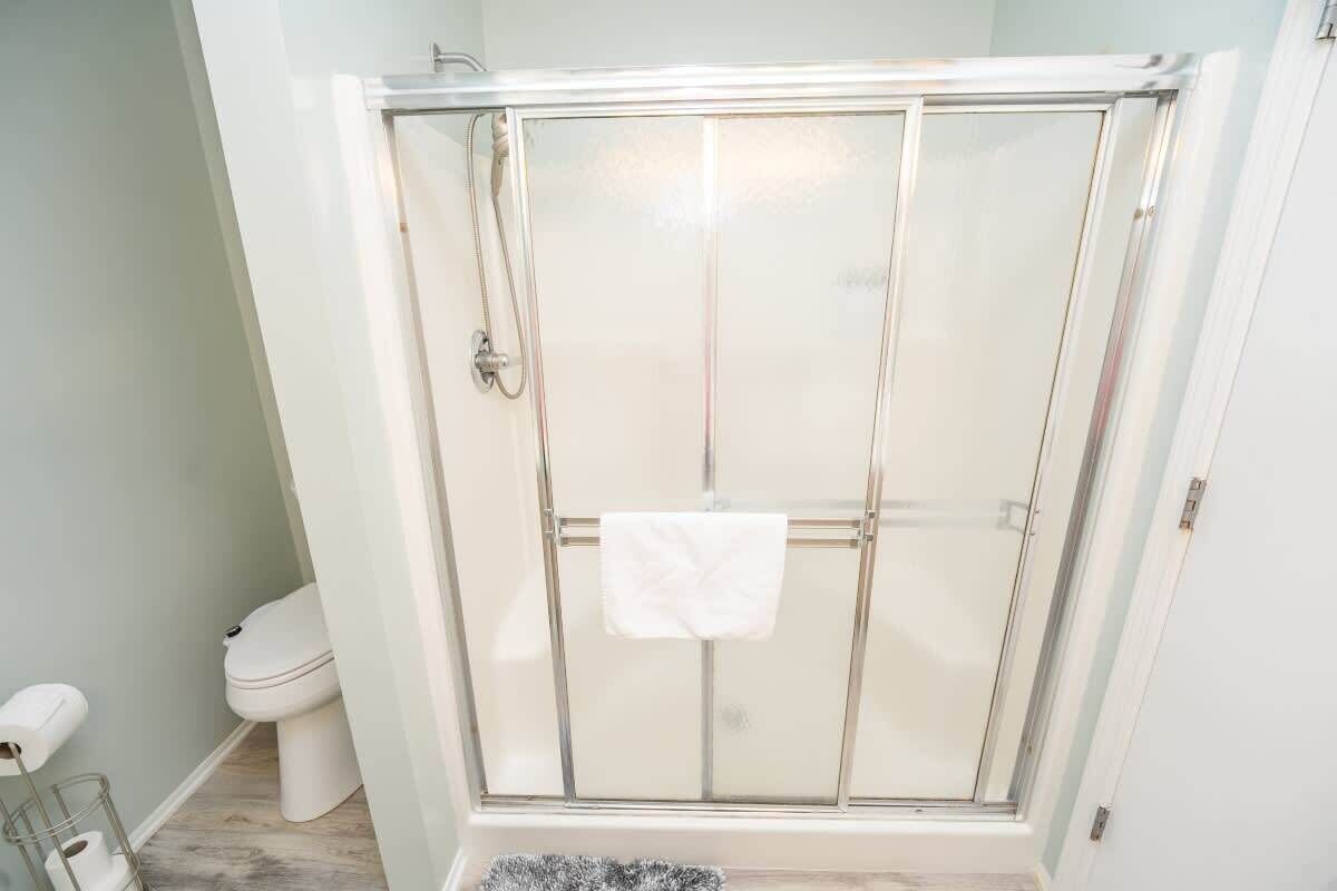 Une salle de bain avec une douche à parois de verre, des toilettes et un porte-serviettes.
