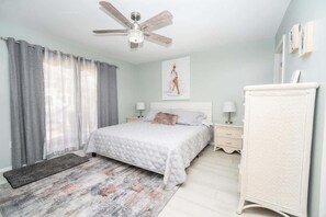 A bedroom with a bed, bedside tables, a dresser, a ceiling fan, and a window with curtains. - Private Pool, 2 Seater Golf Cart, Life Stlye ID's (Lady Lake)