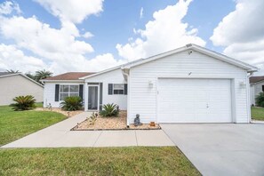 A single-story house with a garage, a front porch, and a well-maintained lawn. - Private Pool, 2 Seater Golf Cart, Life Stlye ID's (Lady Lake)