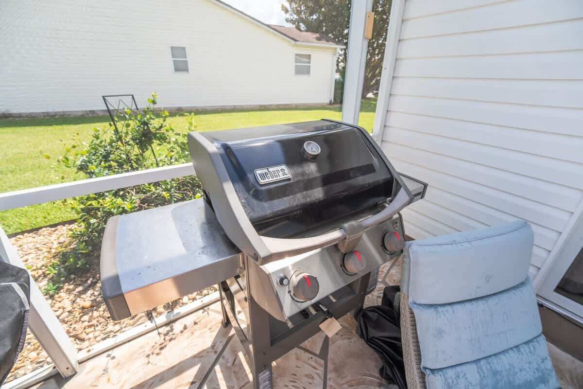 Un barbecue d’extérieur doté d’un panneau de commande, d’une table en métal et d’un coussin bleu.