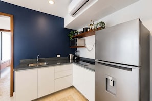 A modern kitchen with a stainless steel refrigerator, a built-in oven, and a countertop with a sink. - Vibrant 2BR apartment (Playa del Carmen)