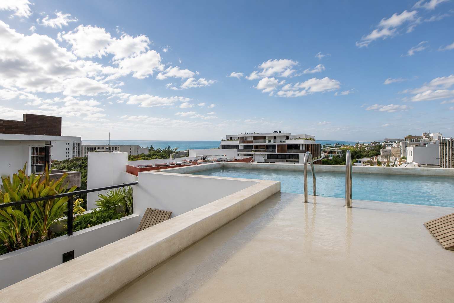 A rooftop pool with a clear view of the ocean and surrounding buildings.