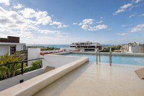 A rooftop pool with a clear view of the ocean and surrounding buildings. - Vibrant 2BR apartment (Playa del Carmen)