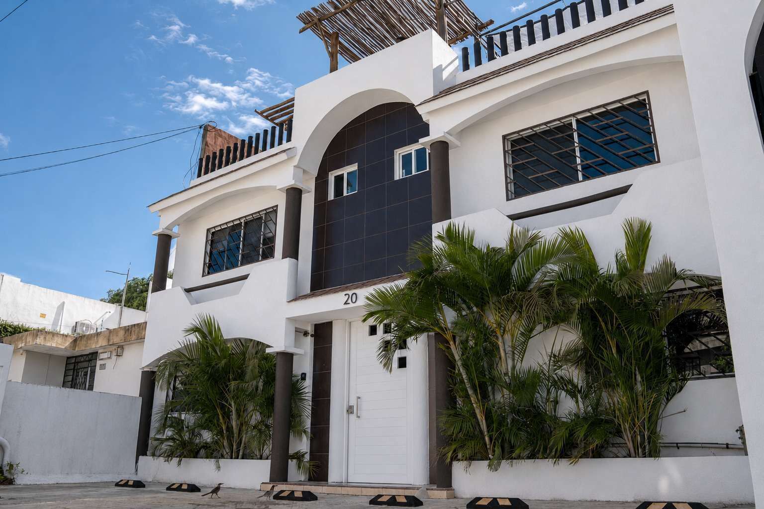 A modern two-story house with a white facade, large windows, and a balcony.