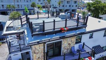 A multi-story building with a rooftop deck, outdoor seating, and a pool.