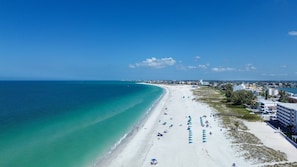 A beach with a clear sky, a sandy shore, and buildings in the background. - Nautilus Island Compound - Roof Deck - Sleeps 16 (Treasure Island)
