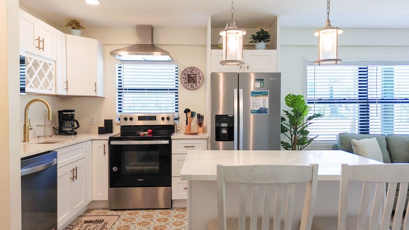 A modern kitchen with white cabinetry, stainless steel appliances, and a central island with seating.