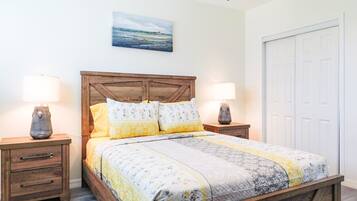 A bedroom with a wooden headboard, two bedside tables with lamps, a bed with floral bedding, and a painting on the wall.