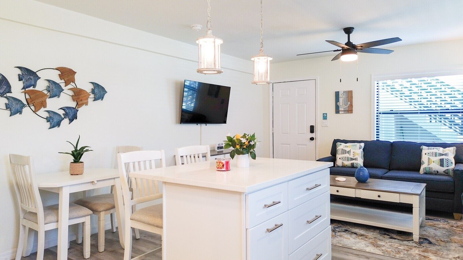 A modern living space with a dining area, a sofa, a ceiling fan, and a TV.