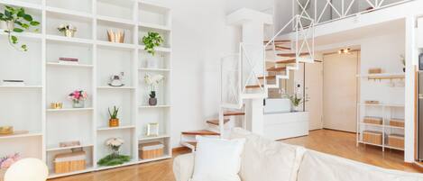 Un interior moderno con un sofá blanco, una estantería blanca y una escalera.
